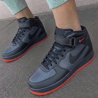 Black high-top sneakers with red soles worn on a concrete surface